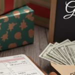 Stack of Christmas presents and gifts next to a budget planner, cash in an envelope, and a phone showing a digital budget tracker, demonstrating planning for a debt-free holiday