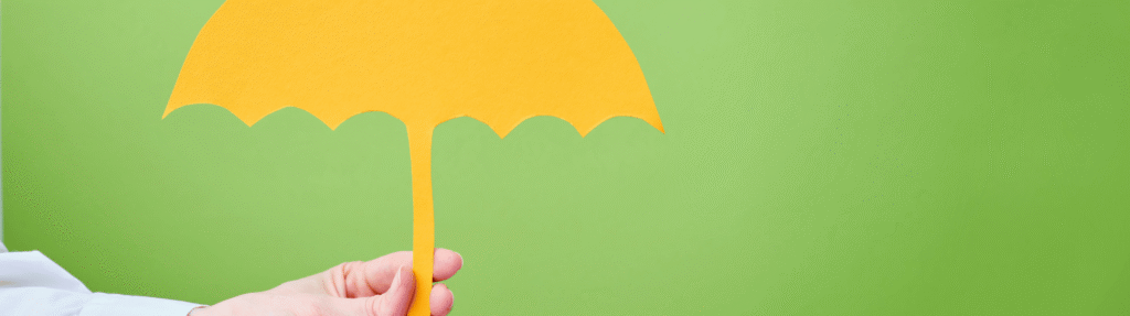 Yellow paper umbrella held against a green background, illustrating life insurance for young families in Milton, Ontario