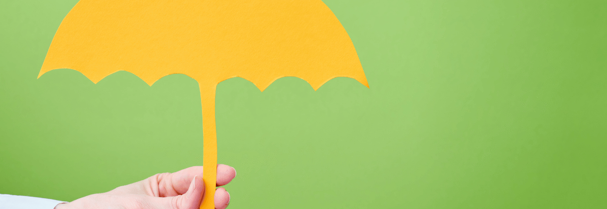Yellow paper umbrella held against a green background, illustrating life insurance for young families in Milton, Ontario
