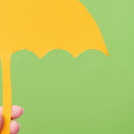 Yellow paper umbrella held against a green background, illustrating life insurance for young families in Milton, Ontario
